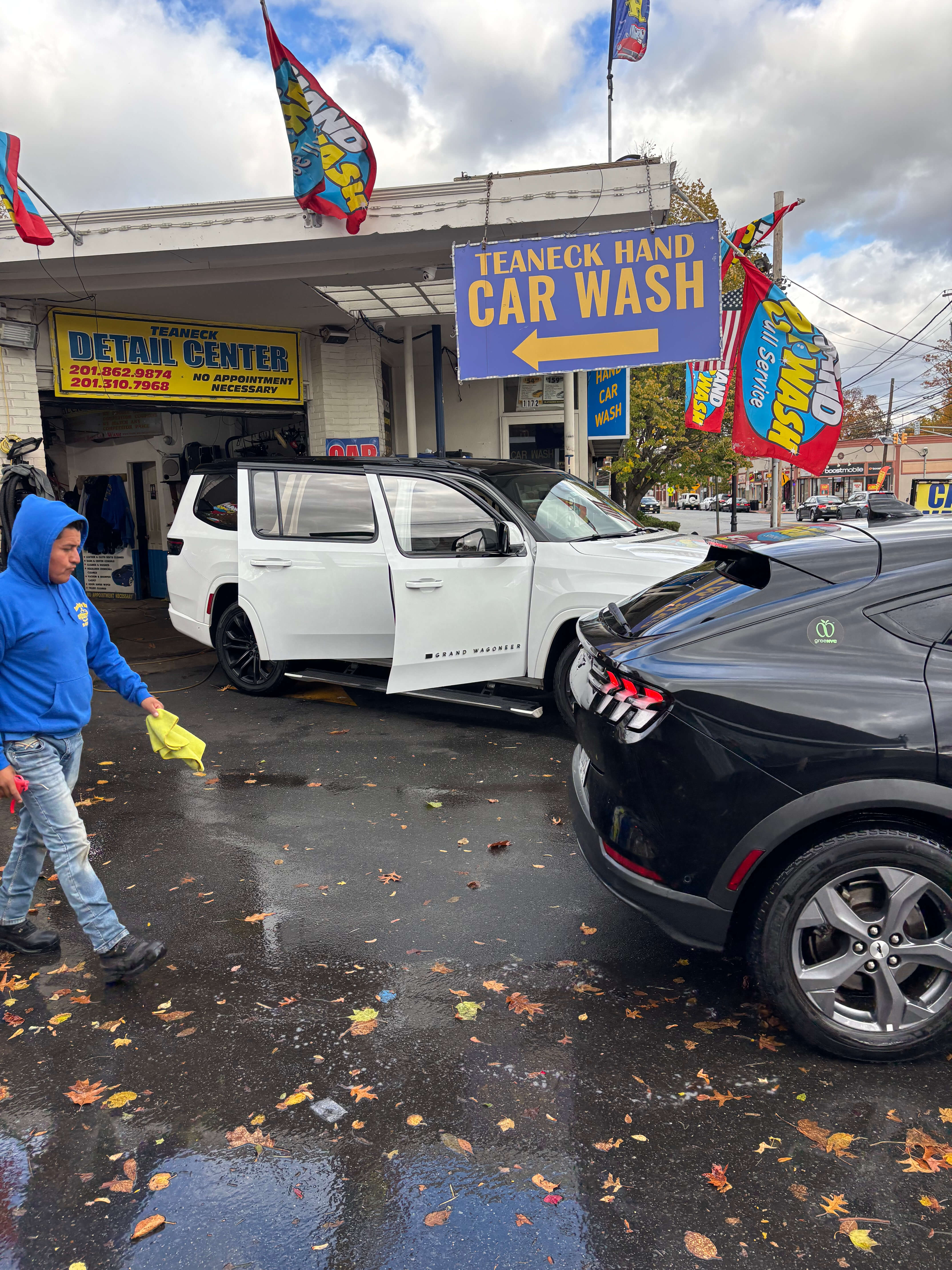 Busy day at Teaneck Hand Car Wash with staff servicing multiple vehicles