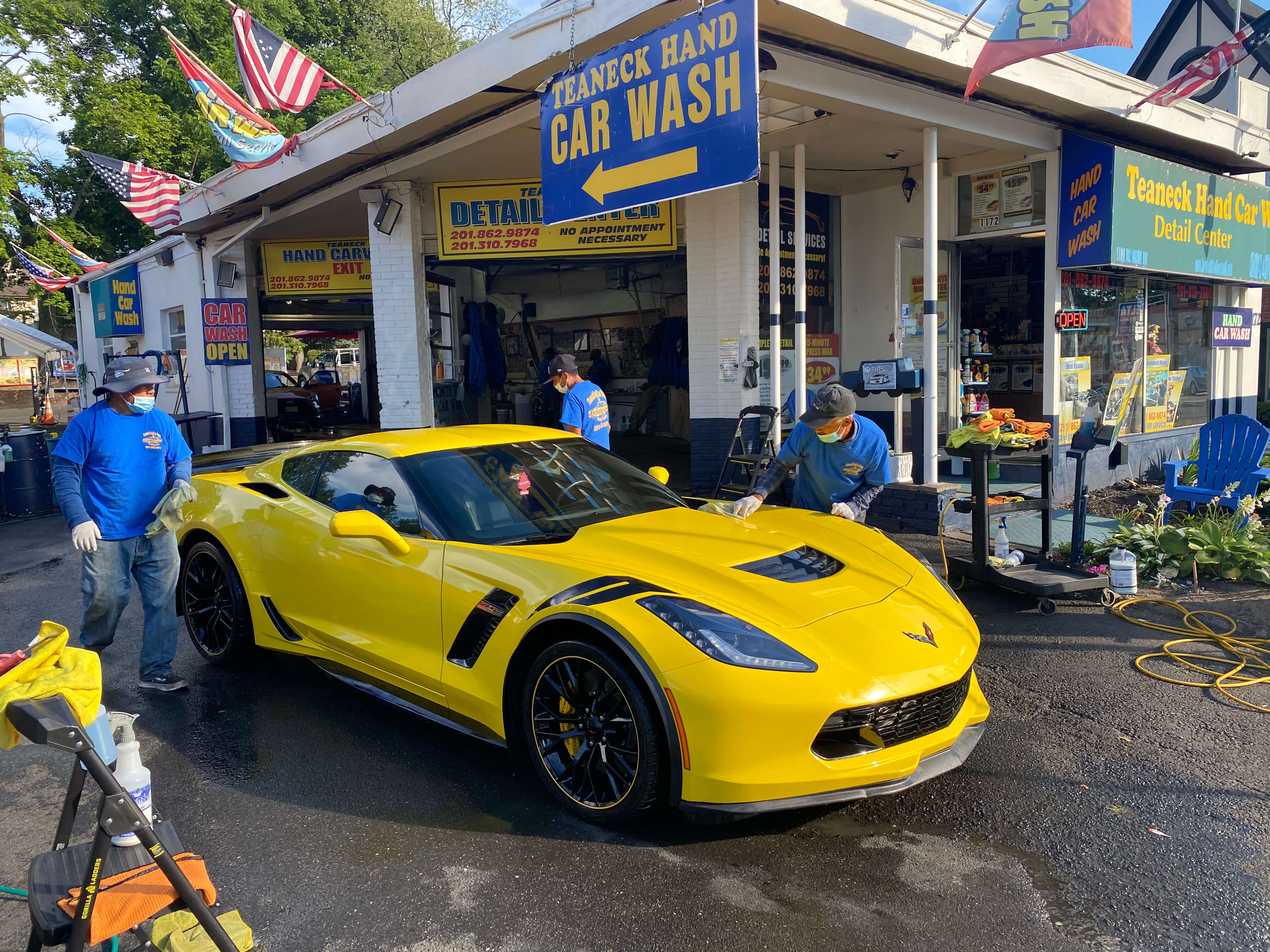 Team detailing a yellow Corvette Z06 at Teaneck Hand Car Wash